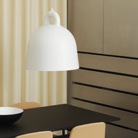 White dome-shaped pendant light, minimal design, contrasting with a black table and beige chairs in a modern setting.