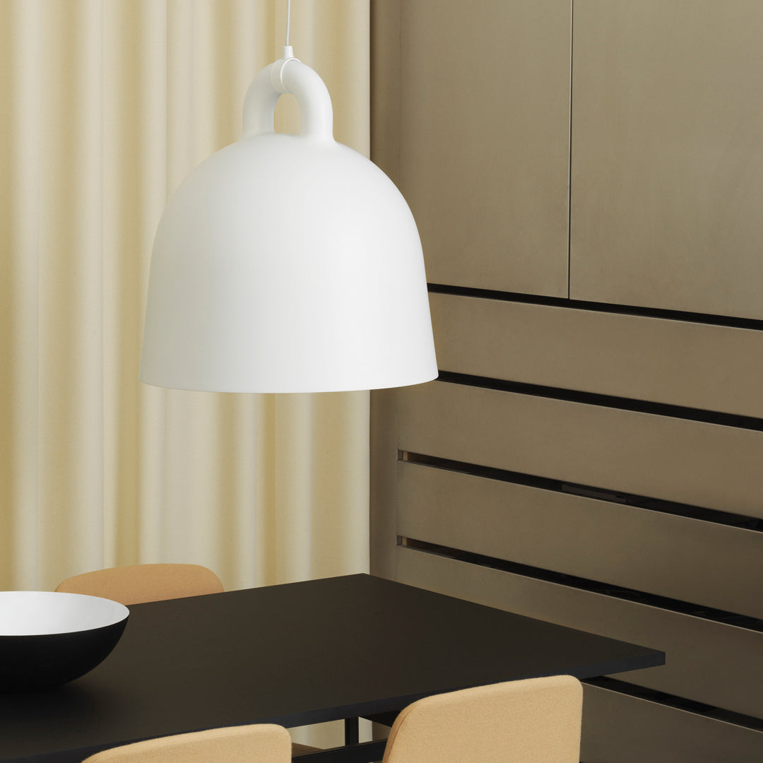 White dome-shaped pendant light, minimal design, contrasting with a black table and beige chairs in a modern setting.