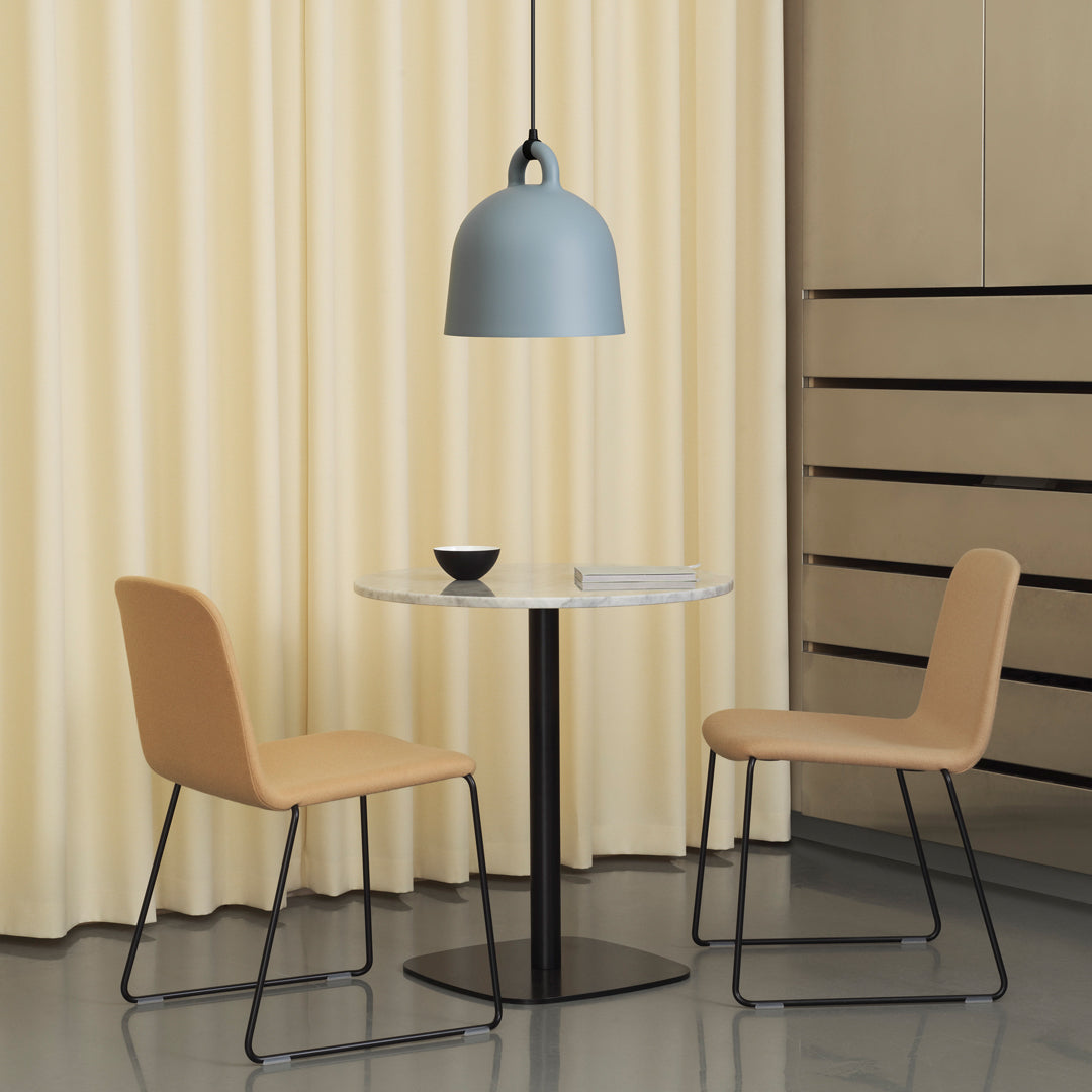 Light blue pendant light, beige chairs, white marble table, and soft yellow curtains create a cozy, modern dining space.