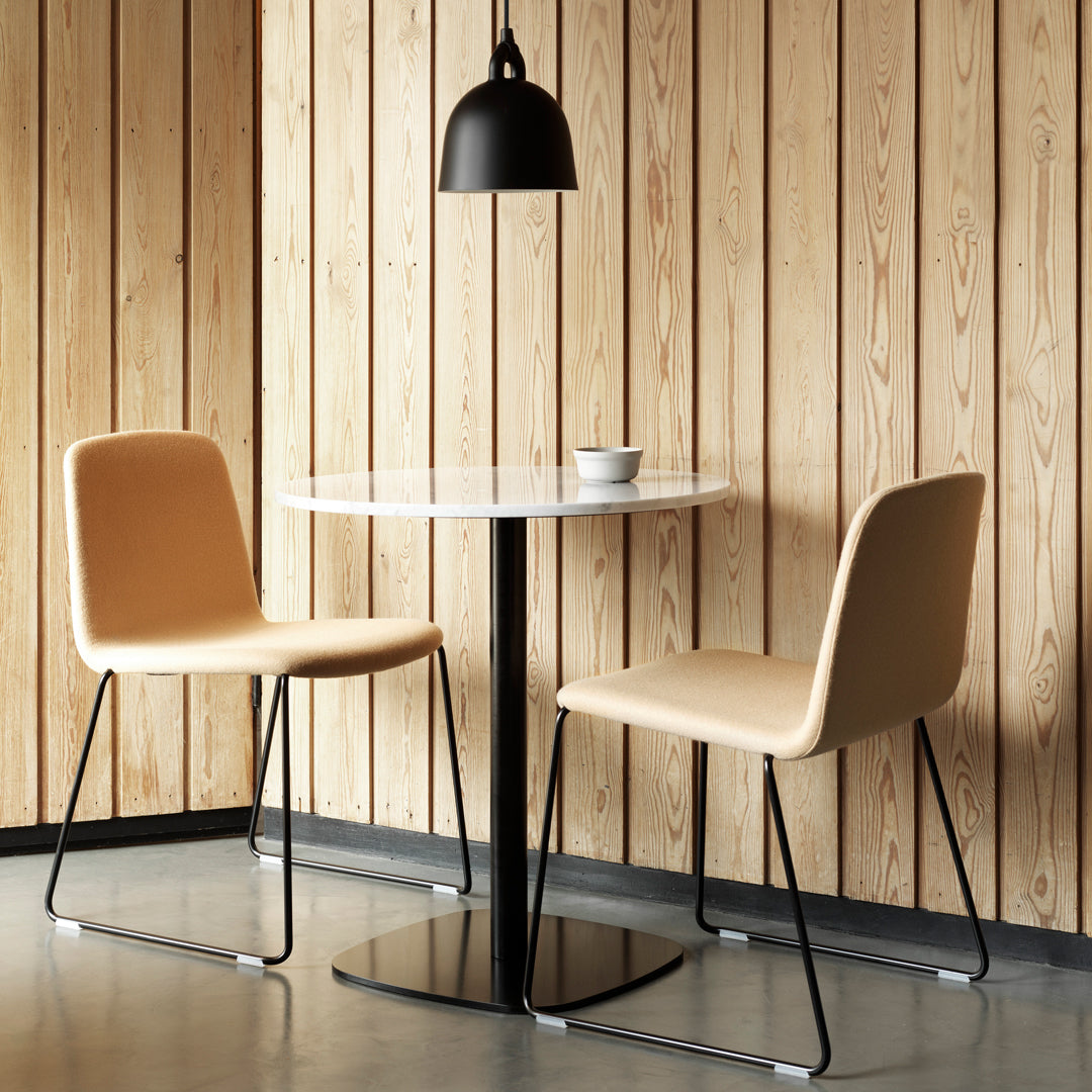 Scandinavian-style dining set featuring tan chairs, a white marble table, and black accents against a wooden backdrop.