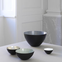 Set of four modern mixing bowls in matte black, pale green, gold, and white, featuring smooth finishes and elegant shapes.
