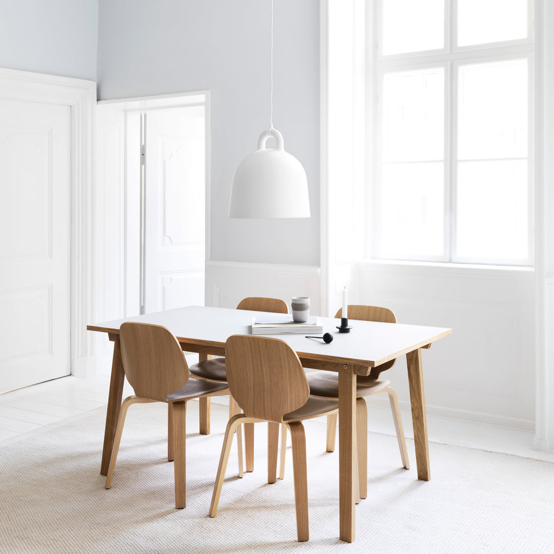 Minimalist dining room with light wood furniture, white surfaces, and soft gray walls, creating a serene, modern ambiance.