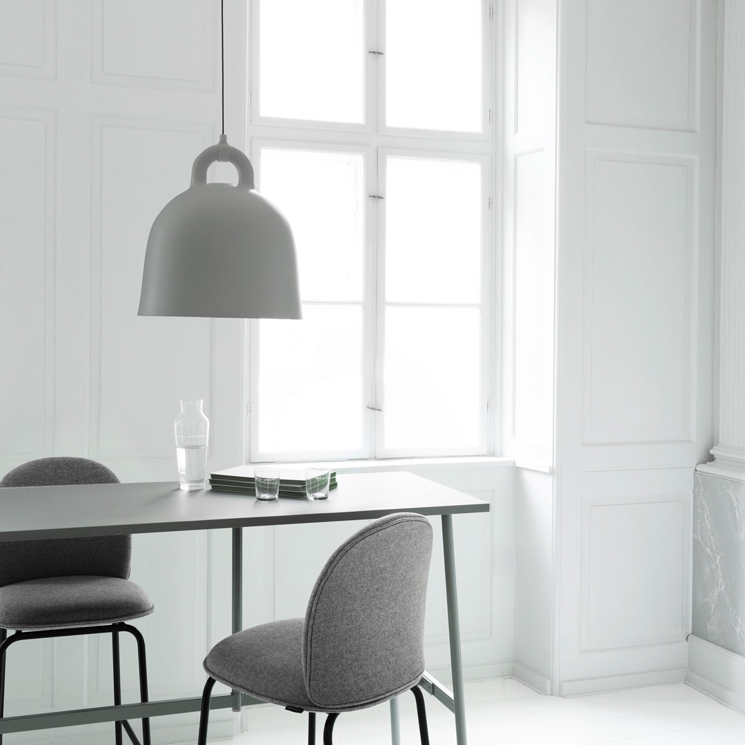 Minimalist gray table lamp and chairs in bright white interior, featuring sleek lines and soft textures.