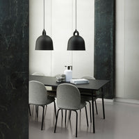 Modern dining scene featuring sleek black pendant lamps, a dark table, and soft gray upholstered chairs against a light backdrop.