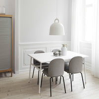 Modern dining room with a white table, gray chairs, and soft cream accents against light wood flooring.