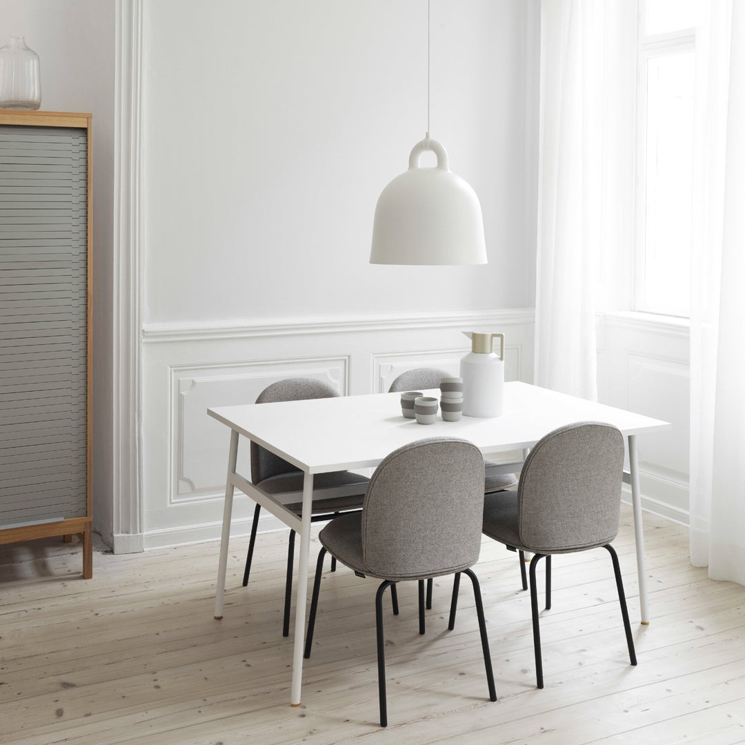 Modern dining room with a white table, gray chairs, and soft cream accents against light wood flooring.