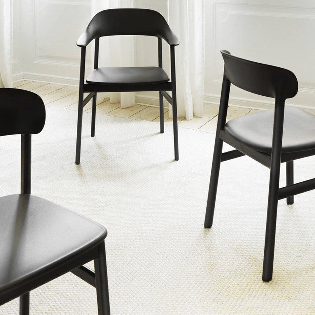 Modern black wooden chairs with a sleek design on a light beige textured rug.
