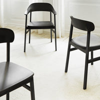 Modern black wooden chairs with a sleek design on a light beige textured rug.