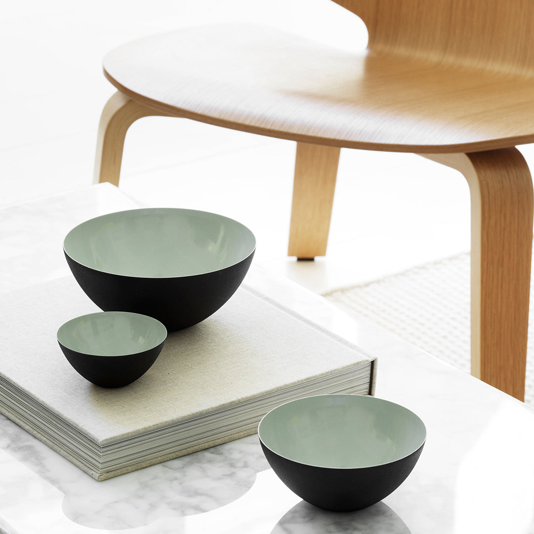 Set of three bowls featuring mint green interiors and sleek black exteriors, displayed on a modern table.