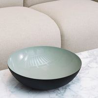 Mint green and black decorative bowl with a smooth finish, placed on a marble surface. Modern and minimalist design.