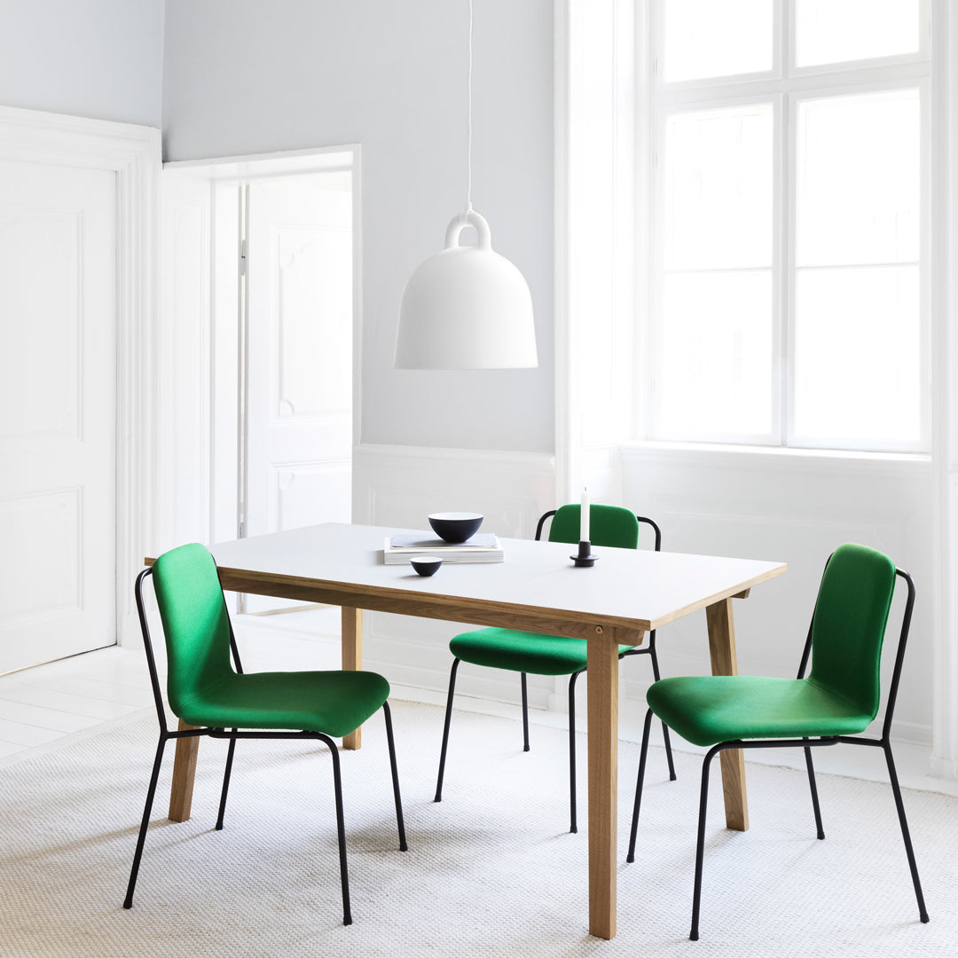 "Modern dining set featuring green chairs and a light wood table in a minimalist white space."