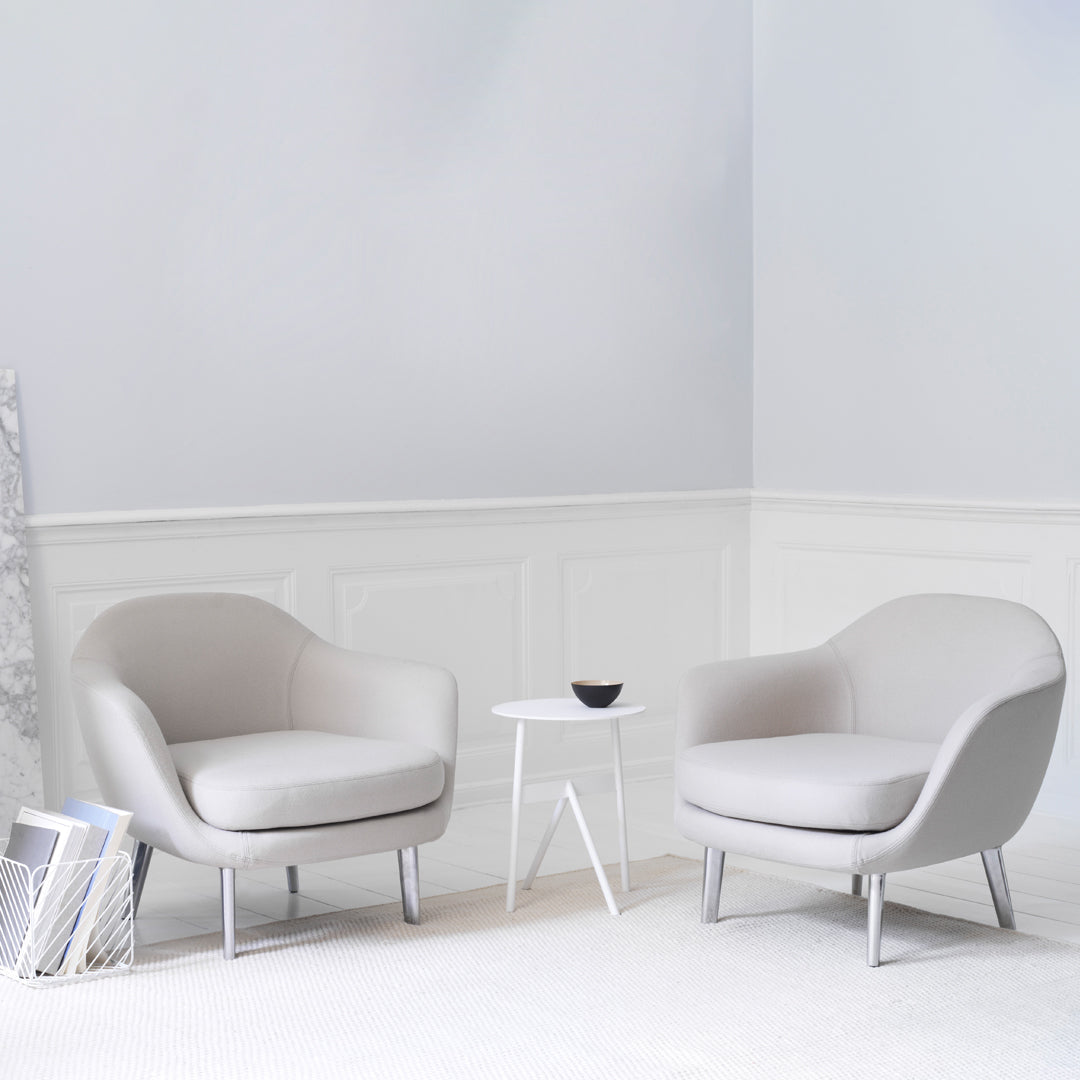 Minimalist gray chairs with smooth, soft fabric and white legs, set against a light, neutral backdrop.