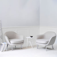 Minimalist gray chairs with smooth, soft fabric and white legs, set against a light, neutral backdrop.
