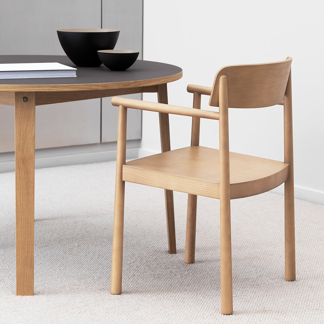 Light wood chair beside a modern black table, featuring smooth lines and a minimalist design in neutral tones.