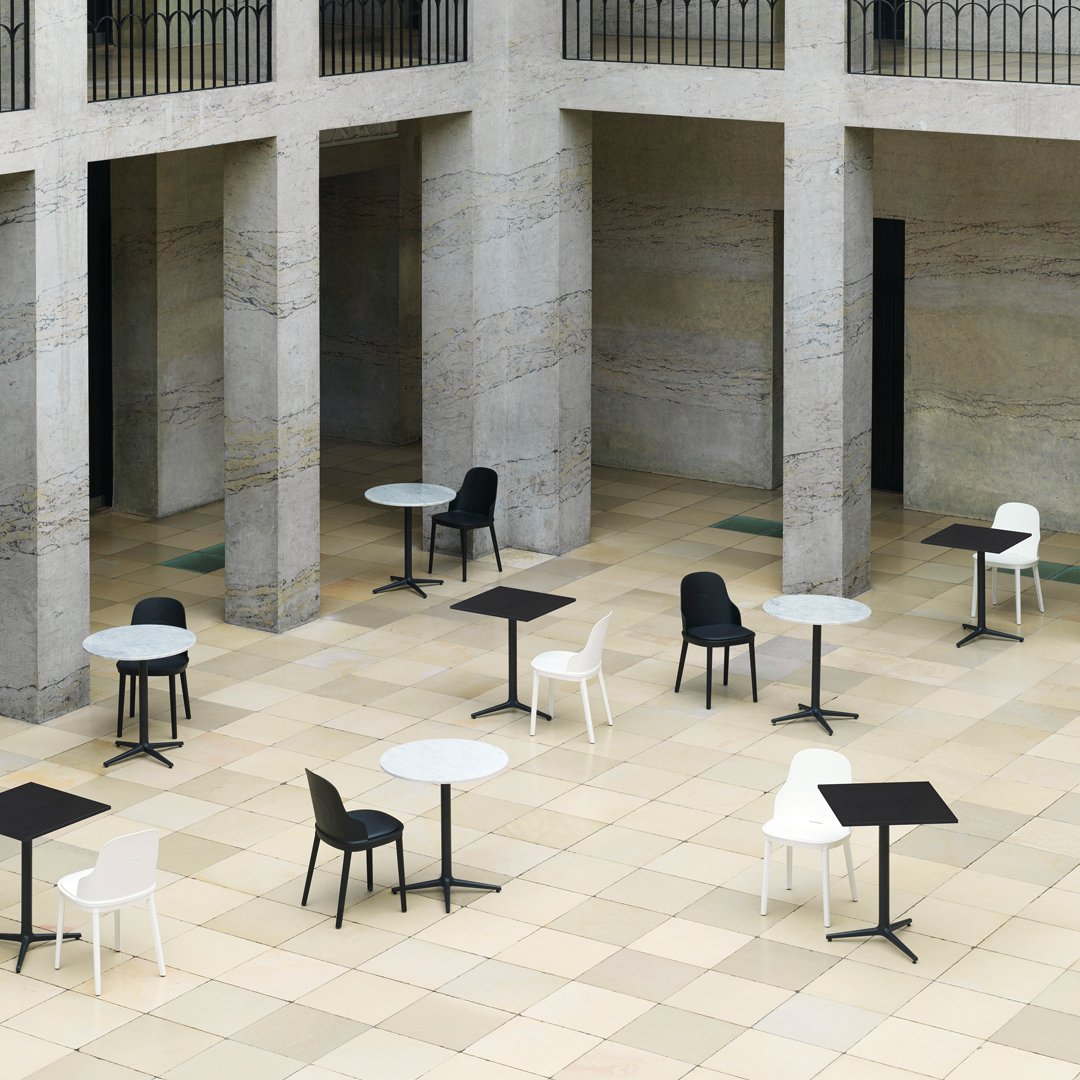 Stylish outdoor tables and chairs in black, white, and gray on a patterned stone floor. Perfect for modern settings.