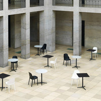 Stylish outdoor tables and chairs in black, white, and gray on a patterned stone floor. Perfect for modern settings.
