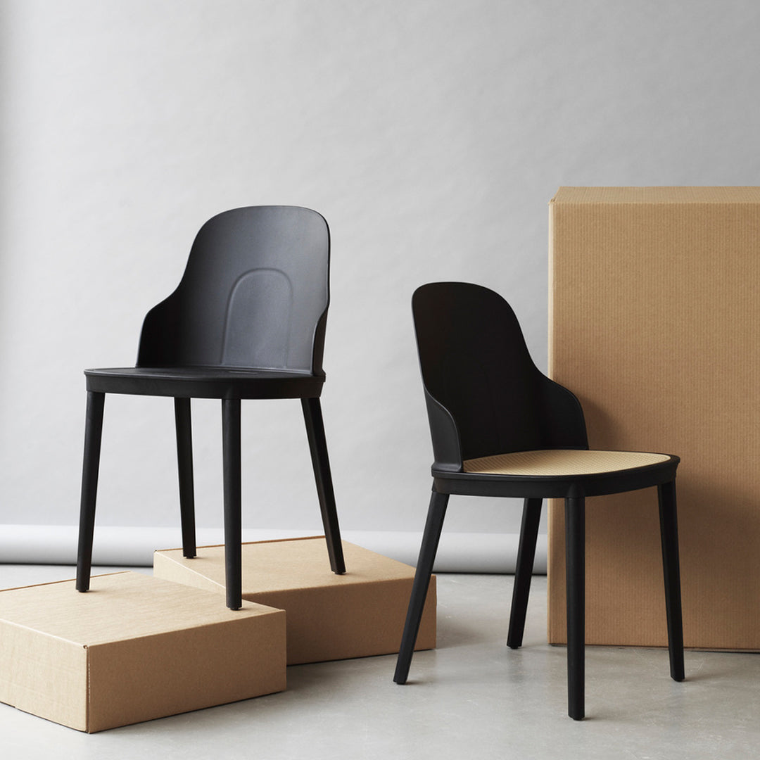 Black modern chairs with smooth contours, featuring a mix of matte and glossy finishes against neutral cardboard.
