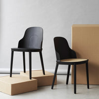 Black modern chairs with smooth contours, featuring a mix of matte and glossy finishes against neutral cardboard.
