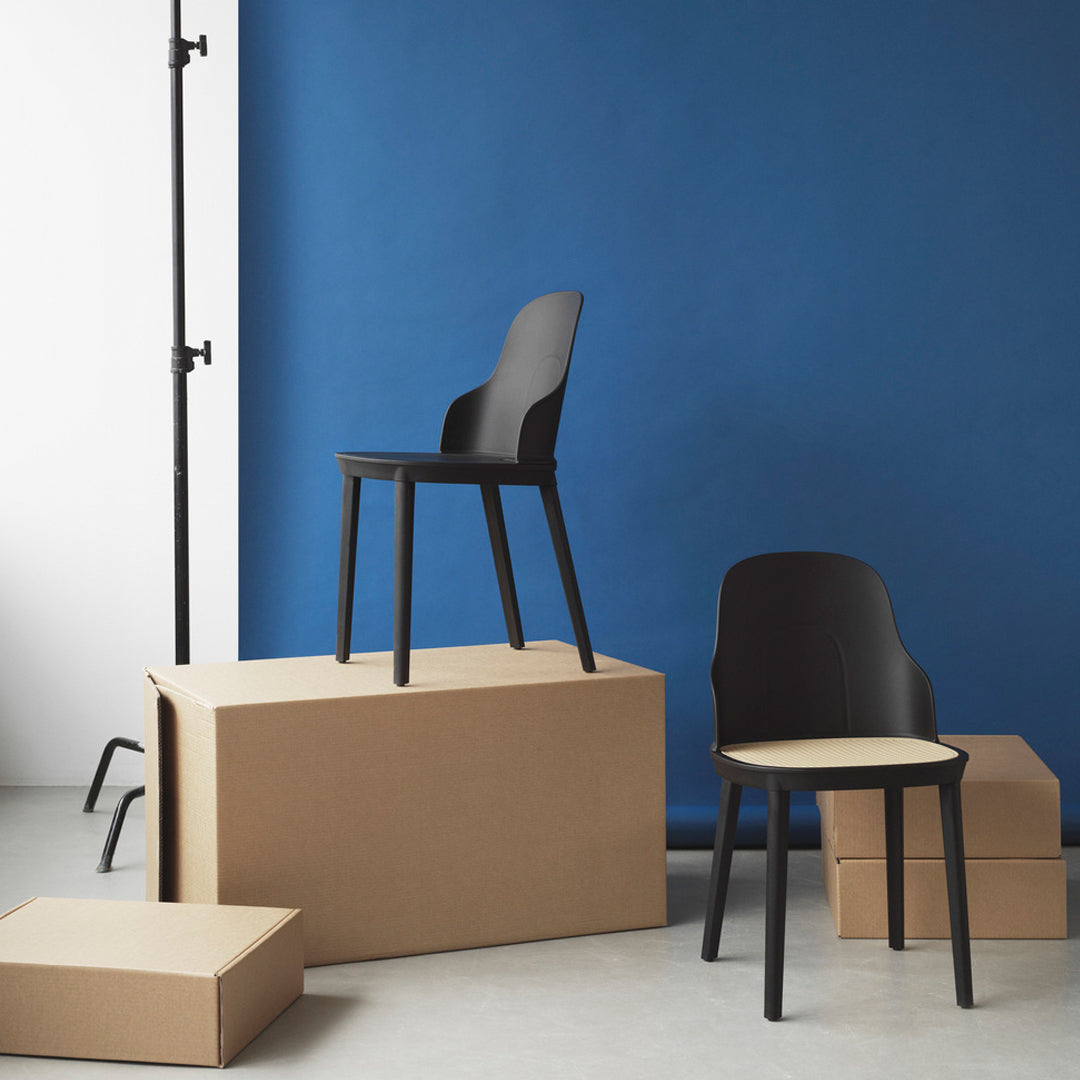 Black minimalist chairs against a bold blue backdrop with neutral cardboard boxes for a modern, stylish contrast.