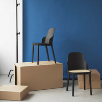 Black minimalist chairs against a bold blue backdrop with neutral cardboard boxes for a modern, stylish contrast.