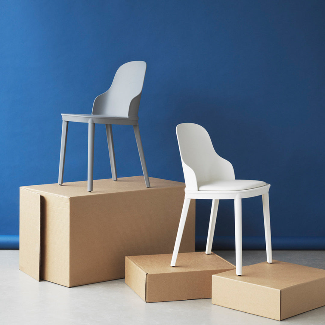 Gray and white modern chairs on cardboard boxes against a vibrant blue backdrop, showcasing sleek design and minimalistic style.