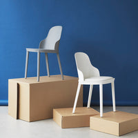 Gray and white modern chairs on cardboard boxes against a vibrant blue backdrop, showcasing sleek design and minimalistic style.