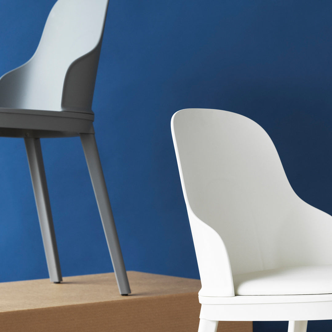 Gray and white modern chairs against a deep blue backdrop, showcasing sleek curves and minimalist design.