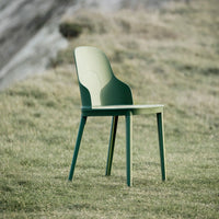 Green chair with a two-tone design, featuring a light green backrest and dark green legs, set against a natural backdrop.