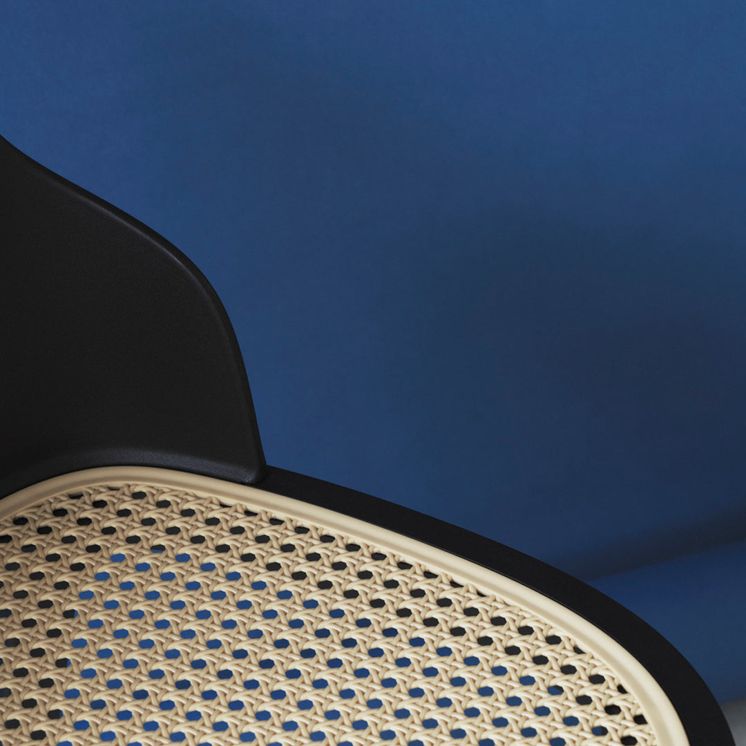 Black and beige patterned chair against a deep blue background, highlighting a modern, minimalist design.