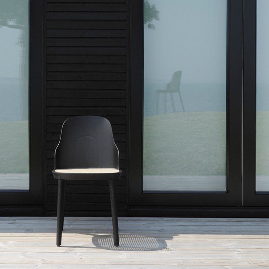 Modern black chair with a smooth finish and light beige seat, set against a minimalist backdrop.