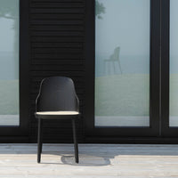 Modern black chair with a smooth finish and light beige seat, set against a minimalist backdrop.