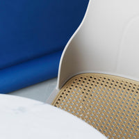 Cream chair with a woven natural rattan seat and blue background, featuring modern, minimalist design elements.