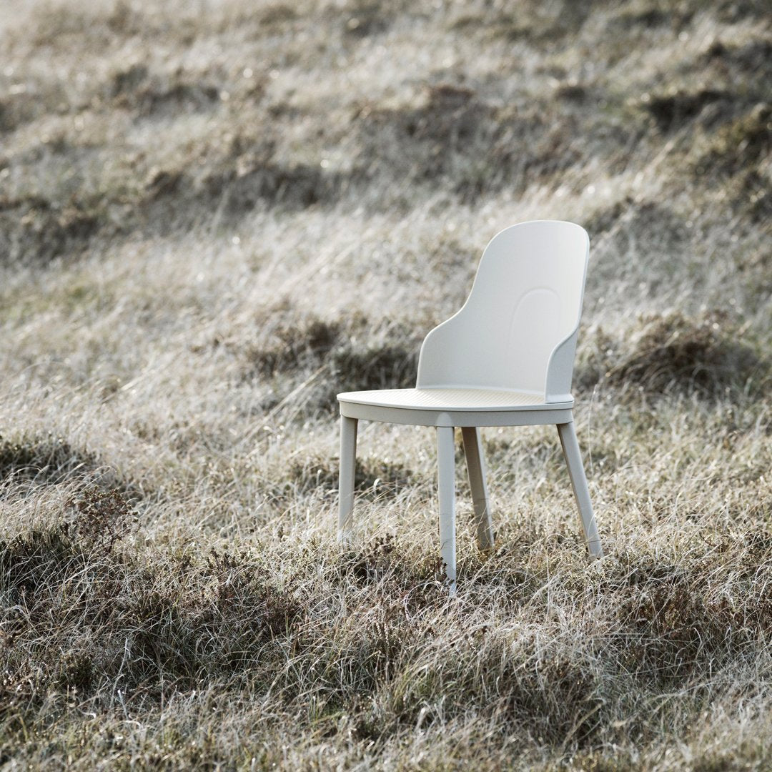 Minimalist white chair on grassy landscape, showcasing sleek lines and a soft, neutral color palette. Perfect for modern decor.