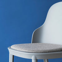 Gray upholstered chair against a vibrant blue background, highlighting a modern design and soft textures.