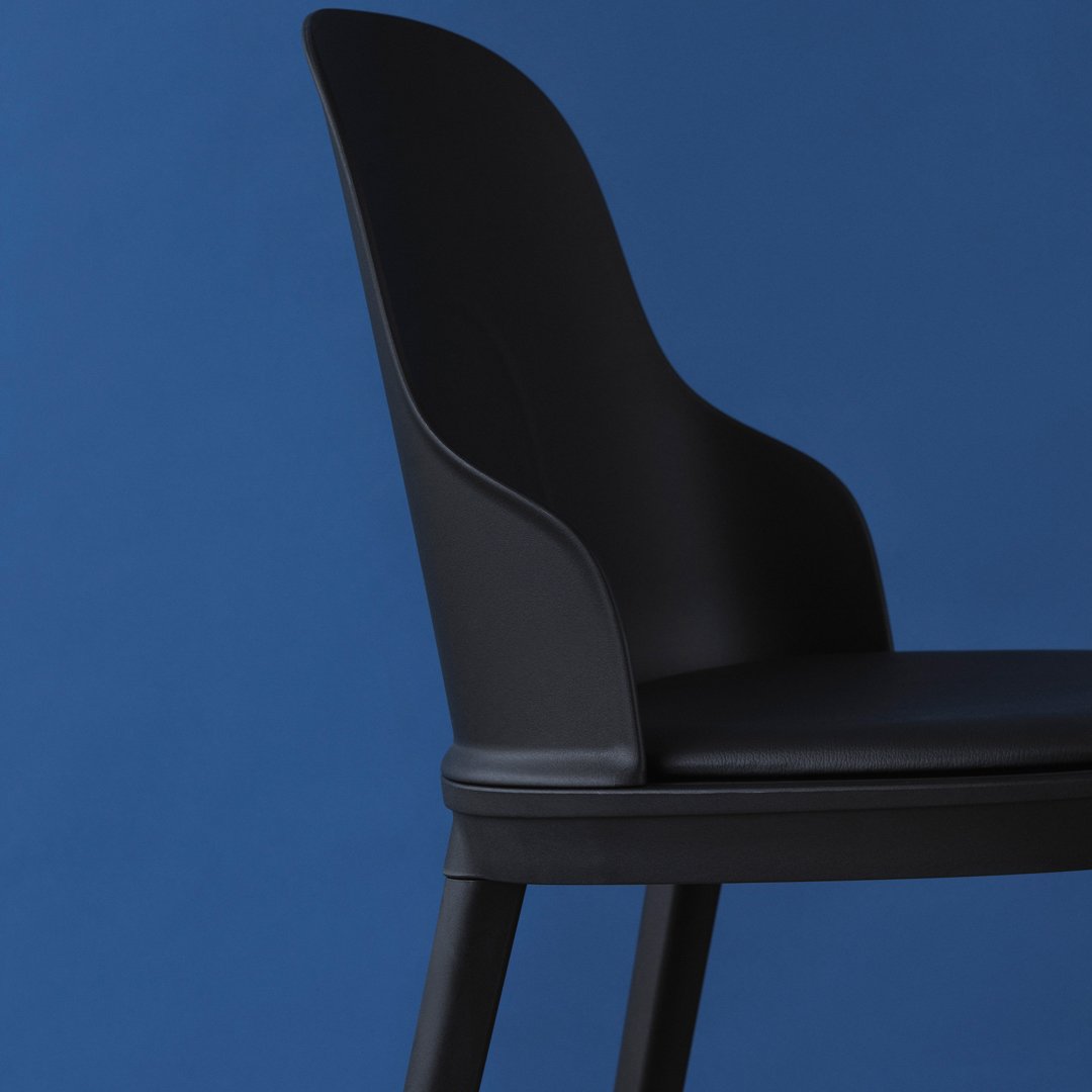 Black chair against a deep blue background, featuring a smooth, curved design with no visible patterns.