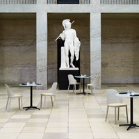 Elegant beige chairs and black tables set against a neutral-toned tiled floor in a spacious, modern venue.