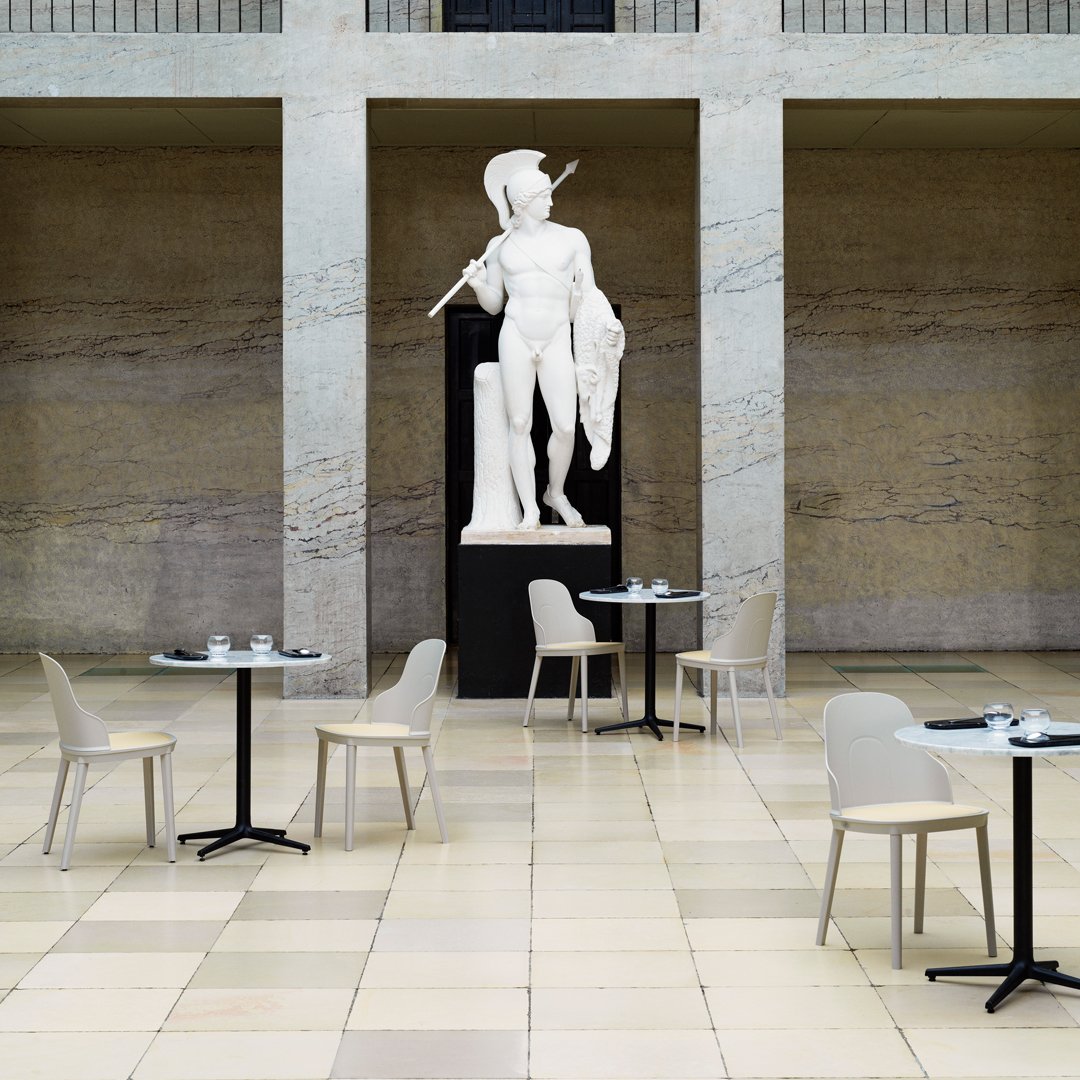 Elegant beige chairs and black tables set against a neutral-toned tiled floor in a spacious, modern venue.