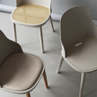 Neutral-toned chairs featuring a woven cane seat and soft fabric upholstery, highlighting modern minimalist design.
