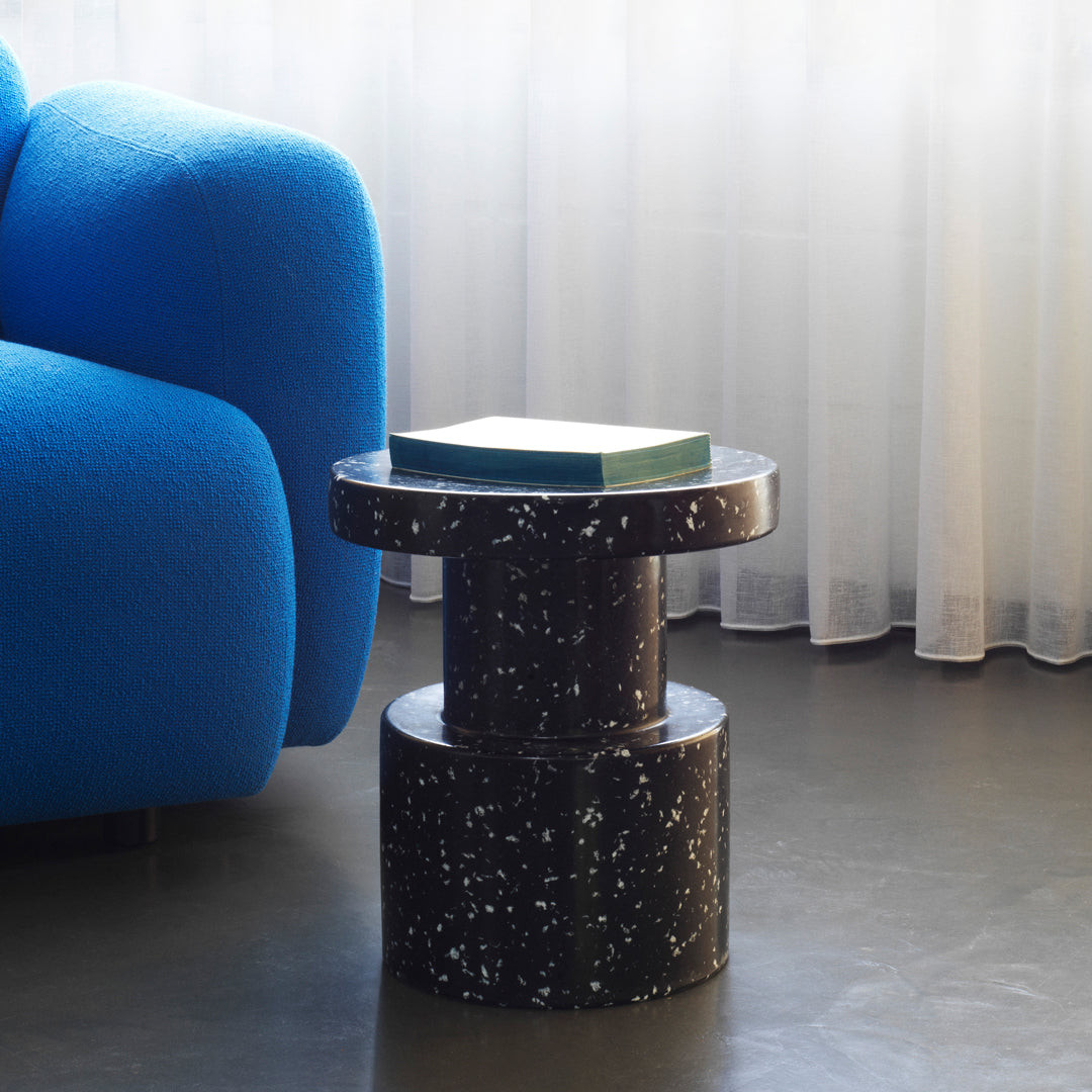 Black speckled side table next to a bright blue couch, adding a modern touch to the elegant interior setting.