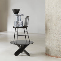 Black and white geometric bar stool with a blue-patterned accent table on a minimalist, light gray background.
