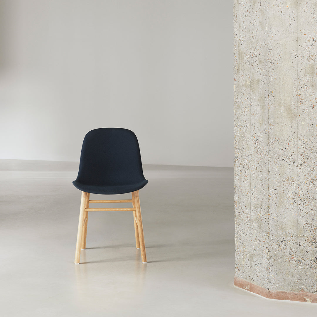 Navy blue chair with wooden legs, complementing minimalist decor and textured wall.