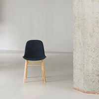 Navy blue chair with wooden legs, complementing minimalist decor and textured wall.