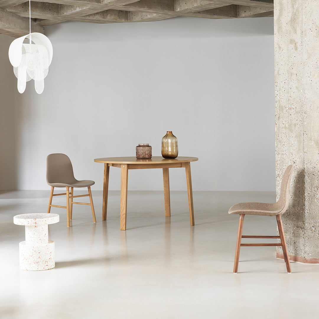 Neutral tones with light wood, soft beige chairs, and a textured white stool enhance a modern minimalistic dining space.