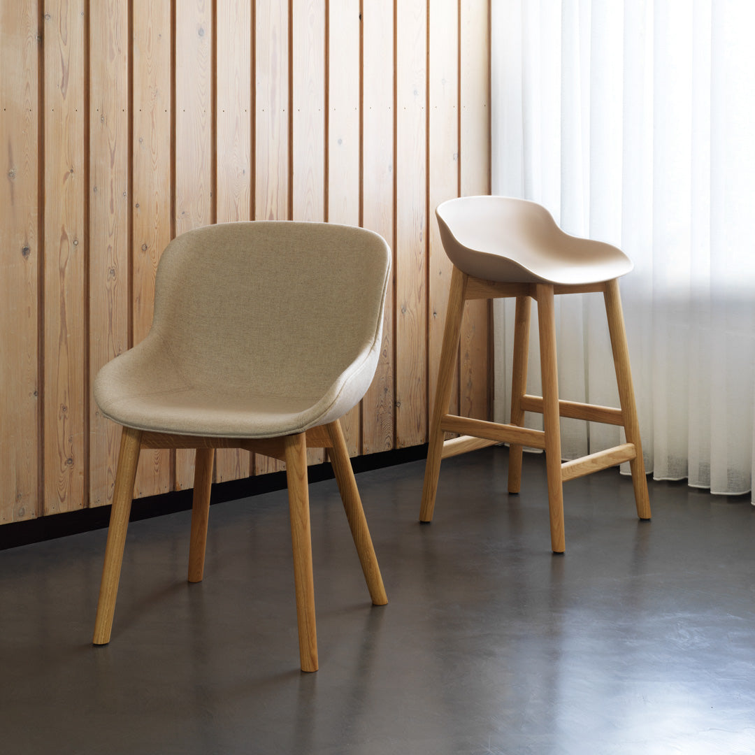 Beige upholstered chairs with minimalist design, paired with natural wood legs against a light wooden backdrop.