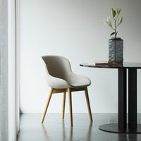 Light beige chair with smooth upholstery and natural wood legs, set against a minimalist backdrop.