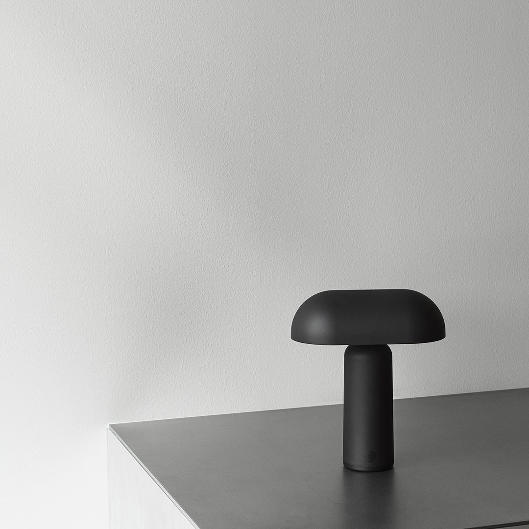 Sleek black table lamp with a modern rounded shade on a minimalist gray surface.