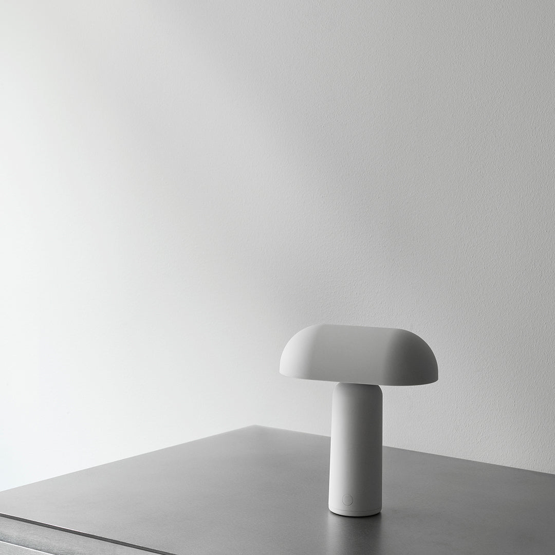 White mushroom-shaped lamp on a sleek gray surface against a minimalist wall for modern decor.