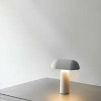 Modern white mushroom-shaped lamp on a sleek gray table, featuring a soft glow. Minimalist design, elegant aesthetics.