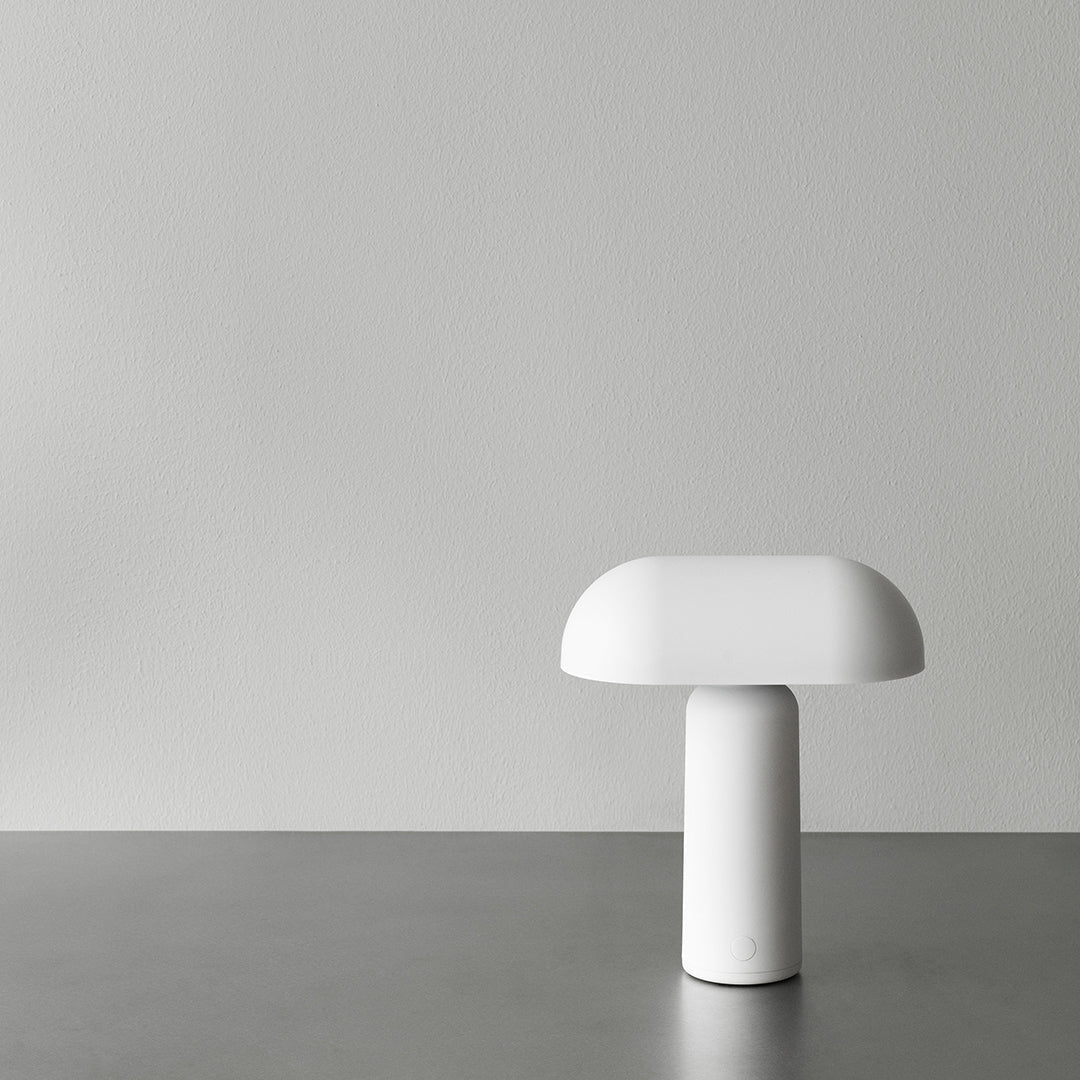 Minimalist white lamp with a smooth, rounded design on a gray surface against a soft gray background.