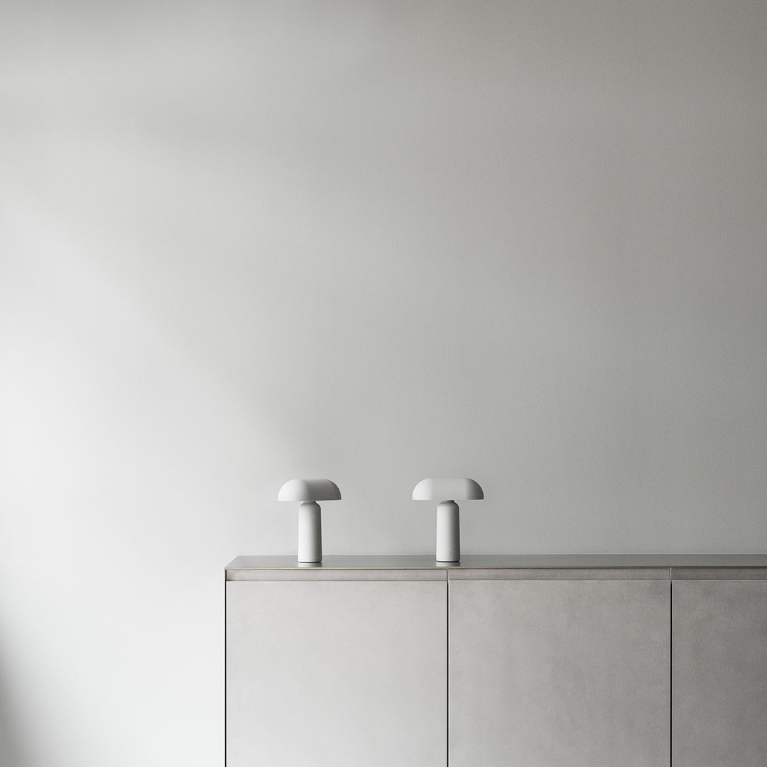 Minimalist gray cabinet with white mushroom lamps on top against a light gray wall, showcasing a sleek, modern aesthetic.